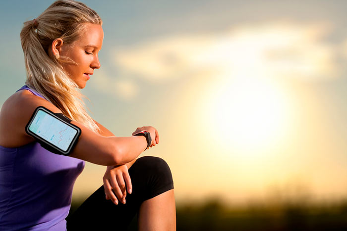 woman pausing from outdoor exercise to view health stats on smartphone