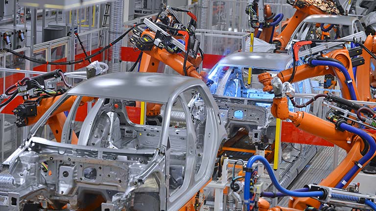 Robotic machinery building a car in a factory